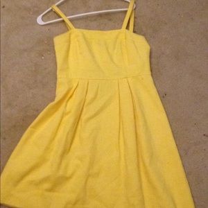 A yellow small strap dress that is pleated